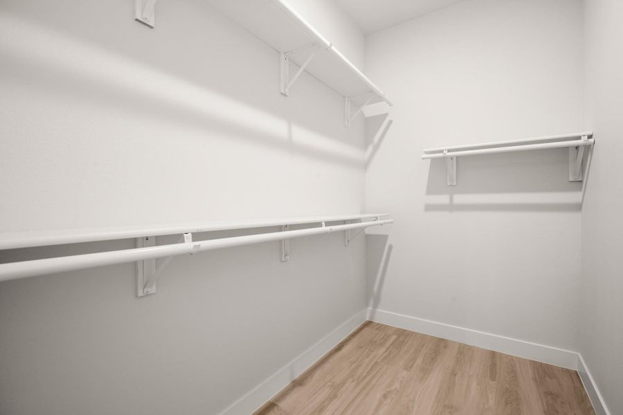 Walk in closet with light wood finished floors