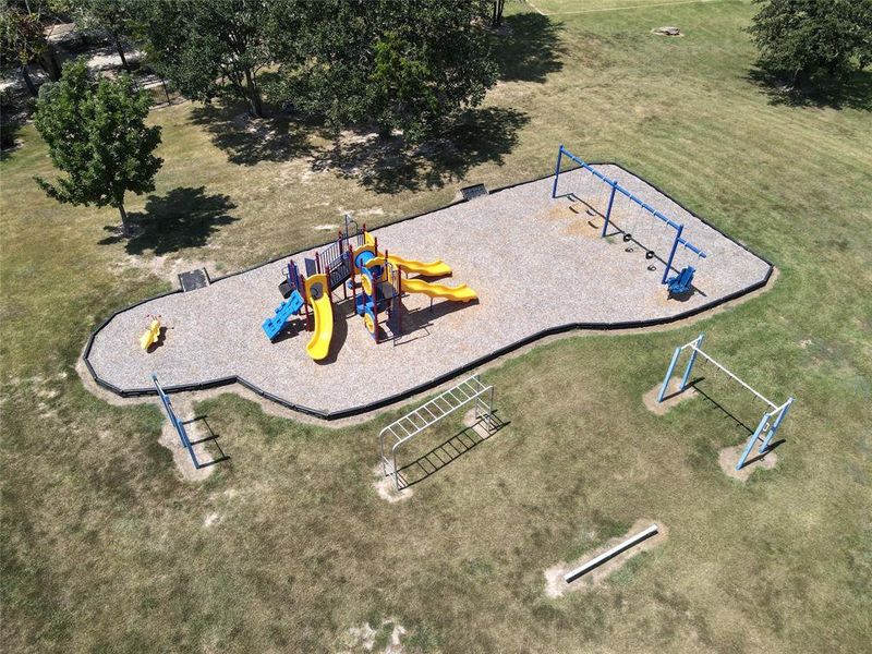 Expansive outdoor recreation area featuring a large central playground structure with multiple slides and climbing elements, a separate swing set, and additional independent monkey bars
