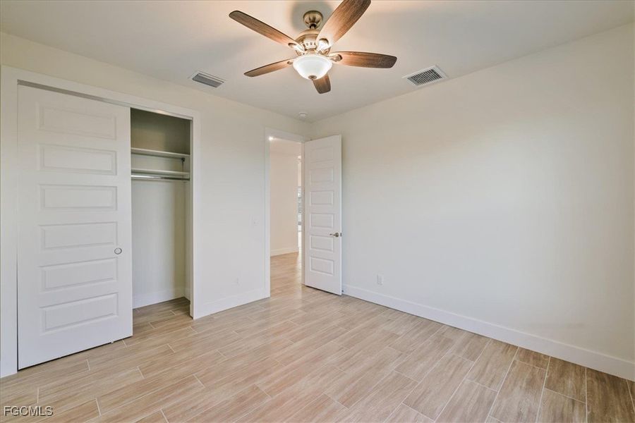 Unfurnished bedroom with wood finish floors, ceiling fan, and a closet