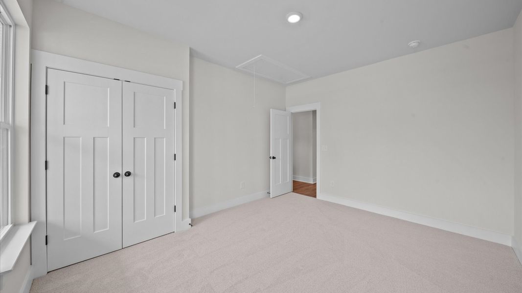 Notable secondary bedroom offering cozy carpeted flooring and a stylish walk-in closet