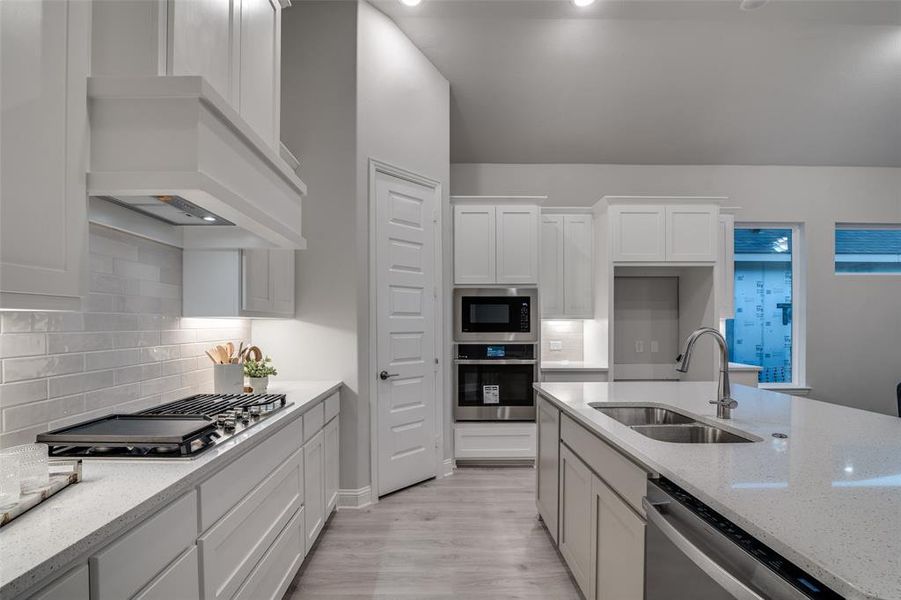 Kitchen featuring light stone countertops, white cabinetry, sink, and stainless steel appliances