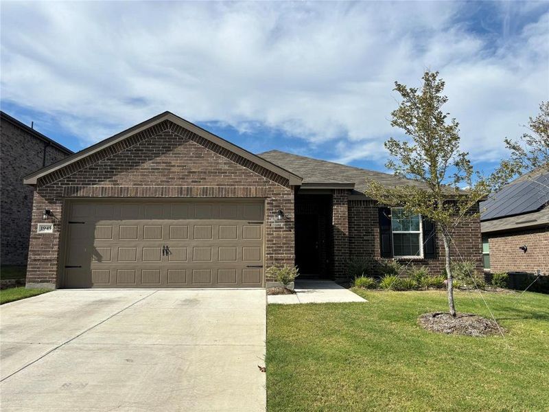 Ranch-style house featuring a garage, brick siding, concrete driveway, and a front lawn