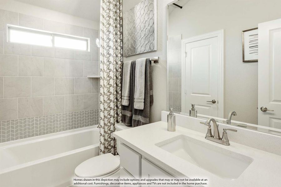 Bathroom with white vanity, undermount sink, soaking tub, and gray tile surround with chevron accent border