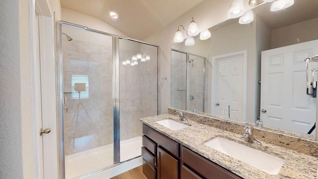 Bathroom with double vanity, a shower stall, and lofted ceiling