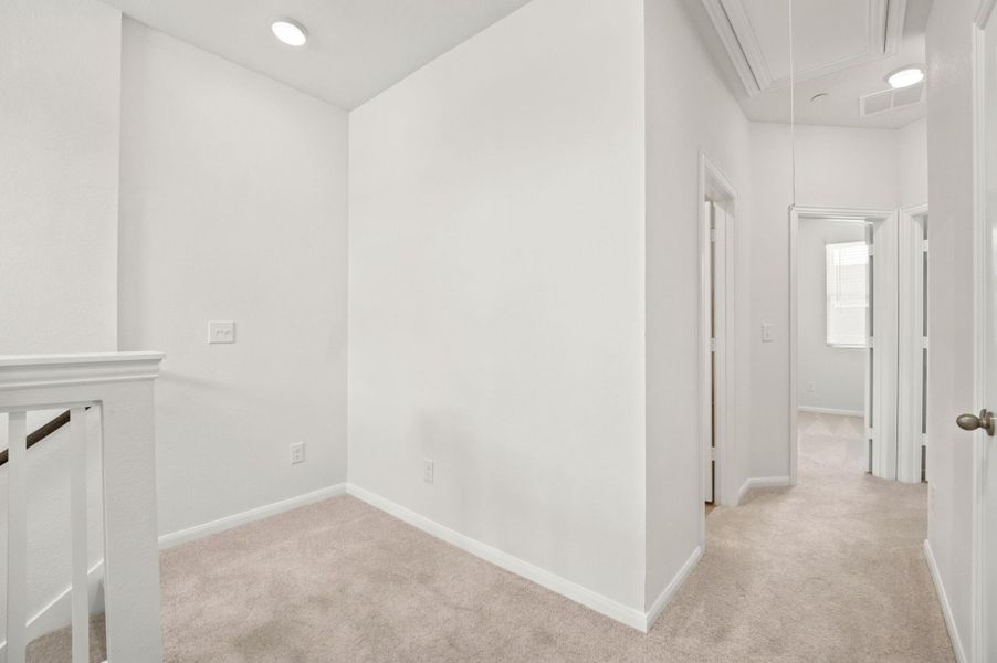 Recessed lighting illuminates this carpeted upper landing leading to upper level bedrooms.