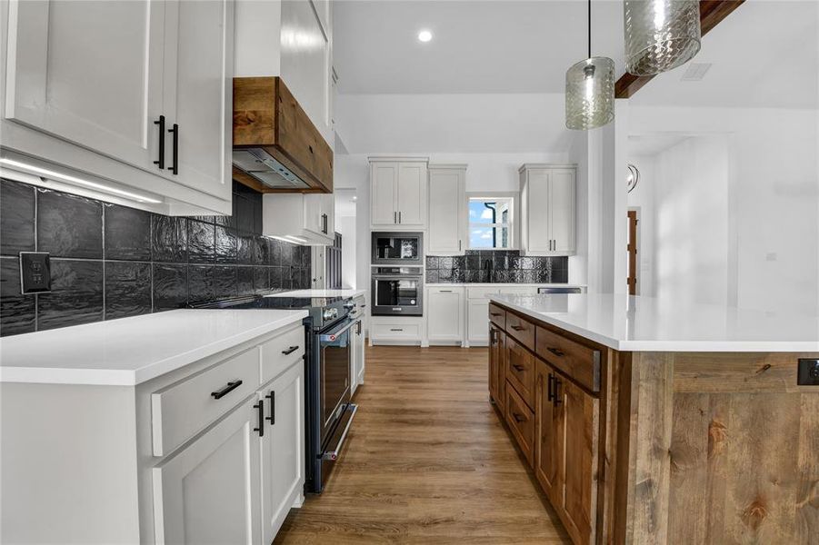 Kitchen featuring stainless steel appliances, white cabinetry, and a kitchen island