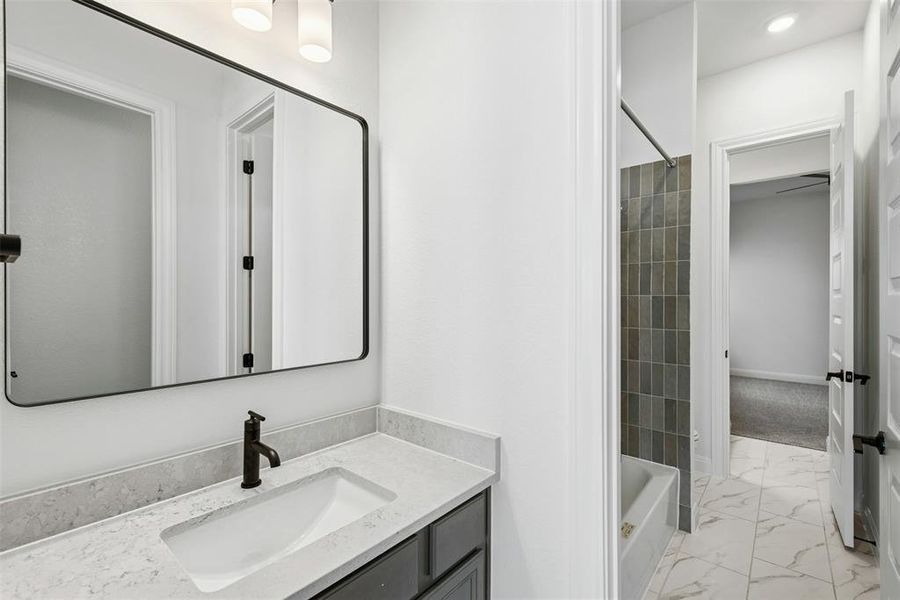 Bathroom vanity featuring a rectangular undermount sink, a light-toned countertop, a matte black faucet, and a black-framed mirror