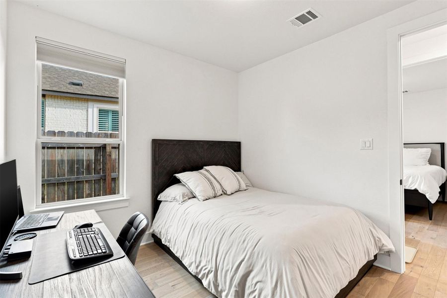 Hardwood floors and a large window create a serene atmosphere in this bedroom.