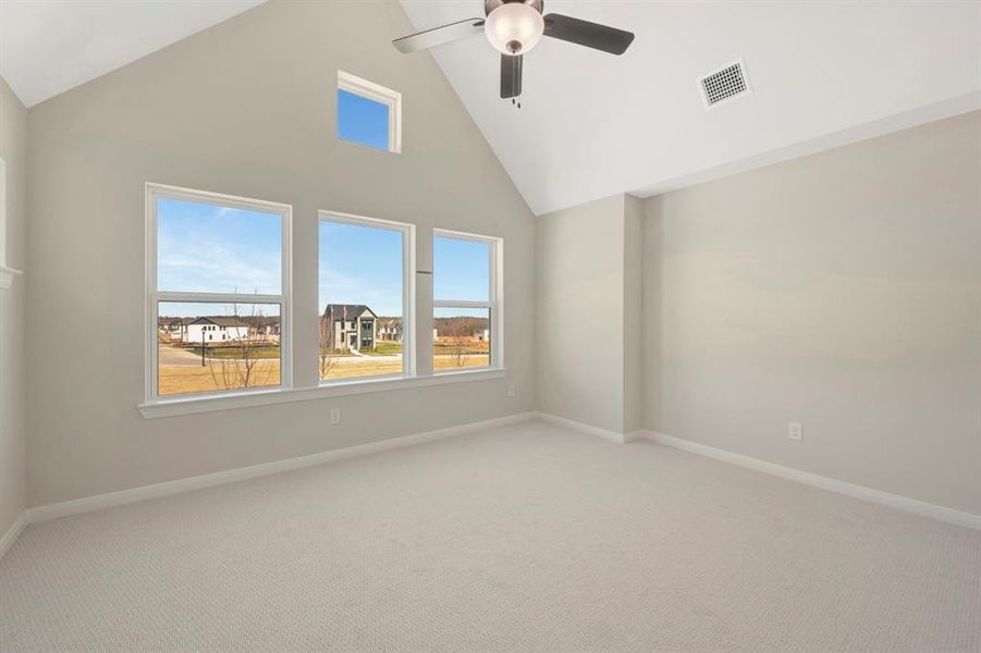 Carpeted spare room featuring a high ceiling and ceiling fan