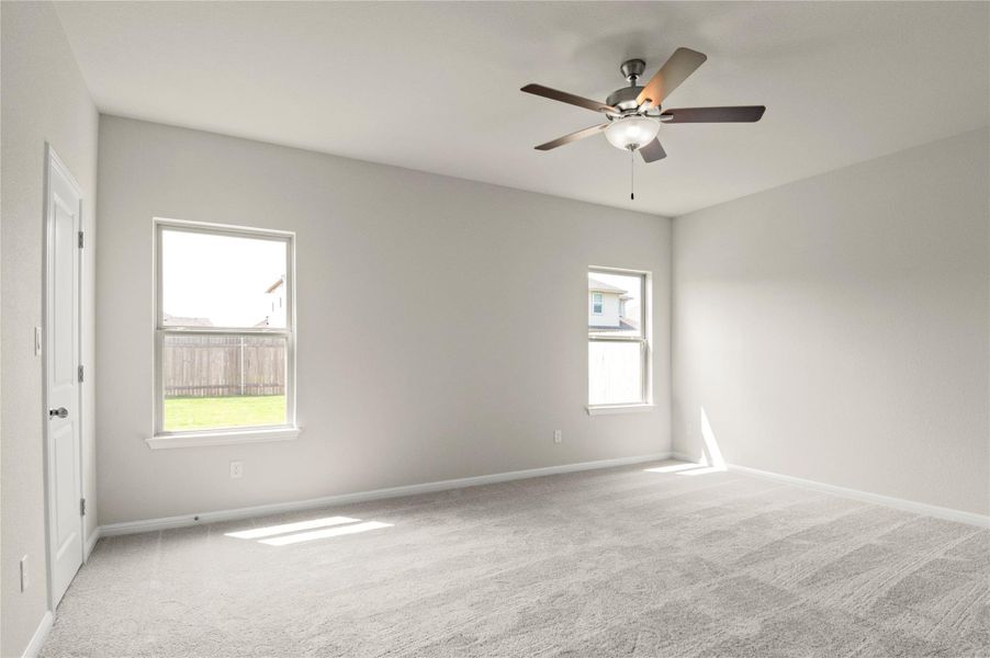 Carpeted empty room featuring plenty of natural light and ceiling fan