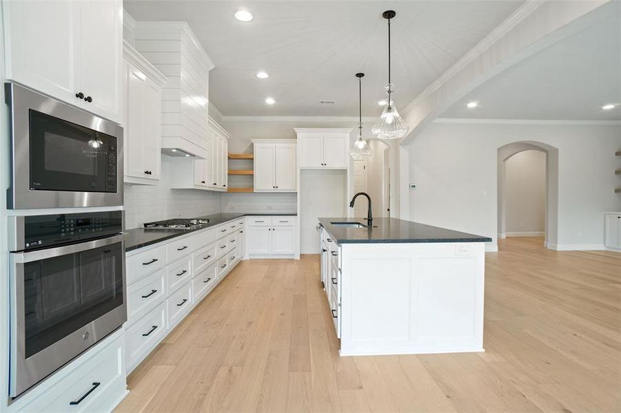 Kitchen featuring white cabinets, backsplash, light hardwood / wood-style floors, and sink