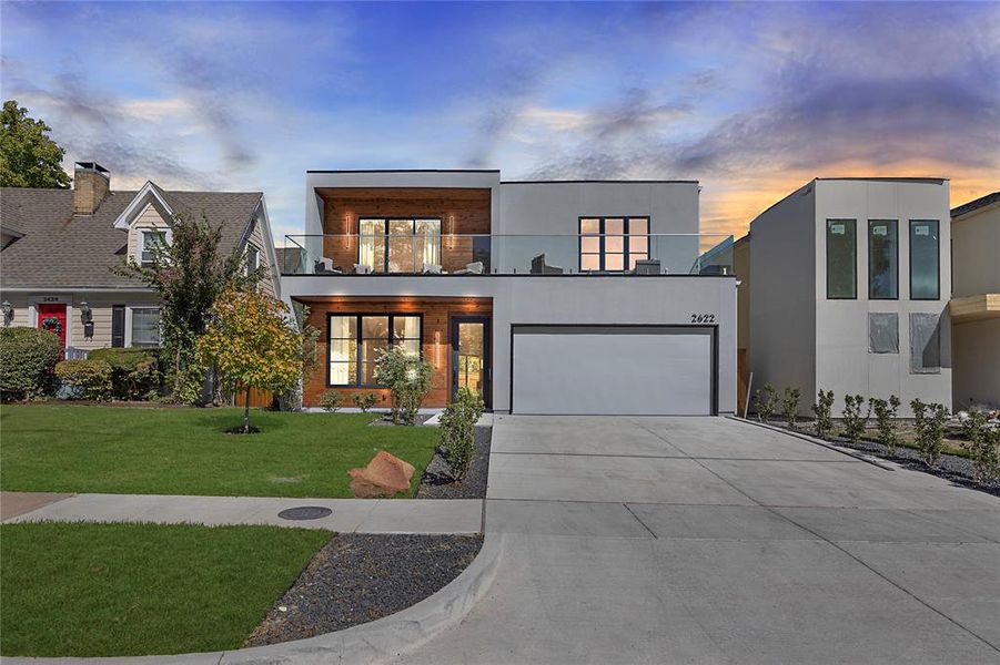 Modern home with a yard, a balcony, and a garage