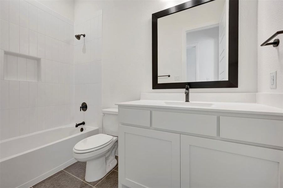 Bathroom featuring vanity, shower / tub combination, and dark tile patterned floors
