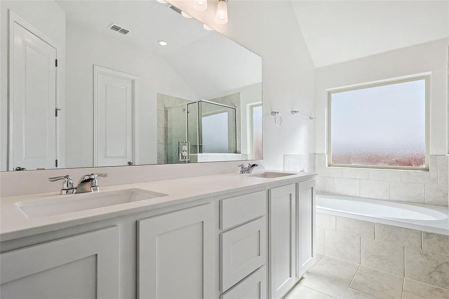 Bathroom with shower with separate bathtub, lofted ceiling, vanity, and tile patterned floors