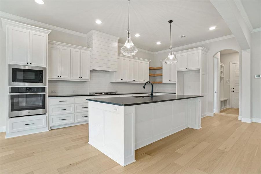 Kitchen with light hardwood / wood-style floors, appliances with stainless steel finishes, white cabinets, and sink