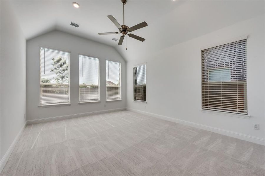 Empty room with ceiling fan, light colored carpet, and lofted ceiling