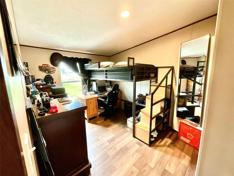 Room featuring wood-finish flooring, a built-in loft bed frame with integrated stairs, and a window with exterior views