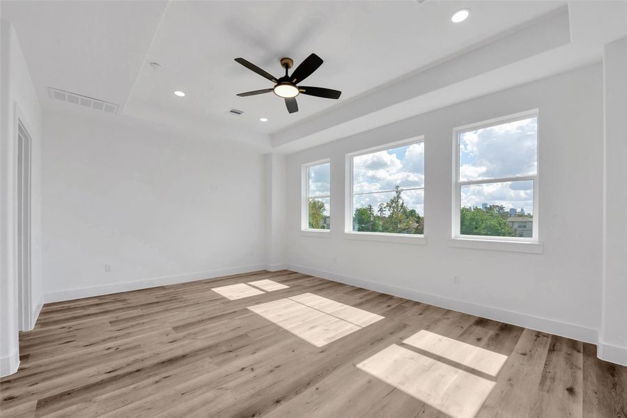 The wall of windows in the primary bedroom bring in lots of natural light. Each bedroom has a ceiling fan with light to help keep the home cool.