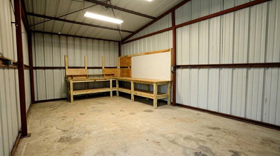 Spacious workshop with concrete floors, built-in workbenches, and plenty of room for tools, hobbies, or storage. Spacious workshop with concrete floors, built-in workbenches, and plenty of room for tools, hobbies, or storage.