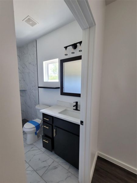 Newly renovated bathroom showcasing sleek black cabinetry, a crisp white vanity, and elegant tiled flooring.