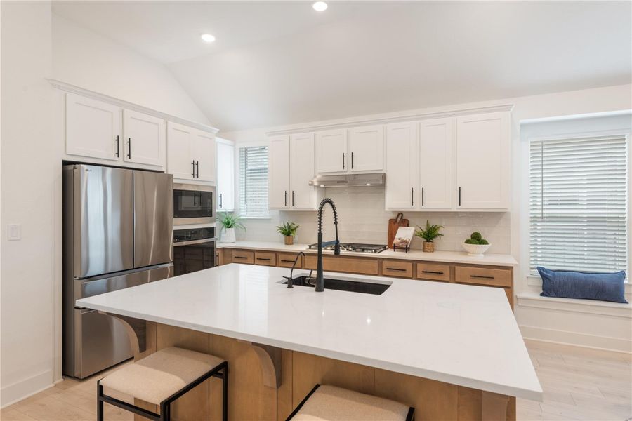 This kitchen showcases a central island with sleek white countertops, ideal for meal preparation and casual dining. This kitchen showcases a central island with sleek white countertops, ideal for meal preparation and casual dining.