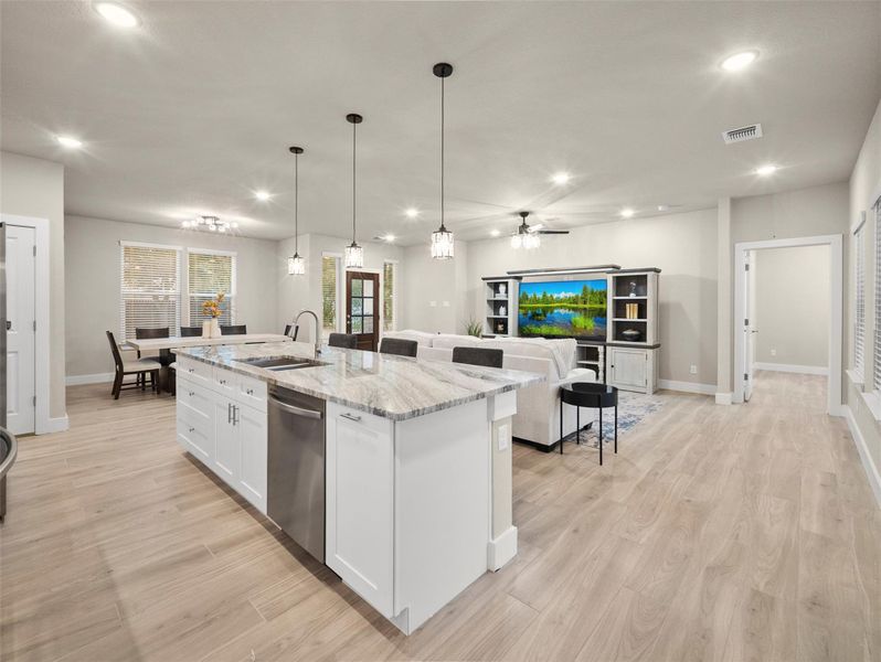 Kitchen featuring white cabinets, light stone countertops, open floor plan, pendant lighting, and dishwasher Kitchen featuring white cabinets, light stone countertops, open floor plan, pendant lighting, and dishwasher