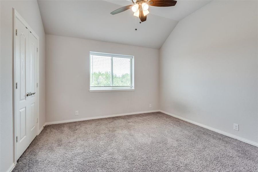 Unfurnished bedroom with lofted ceiling, carpet flooring, and ceiling fan