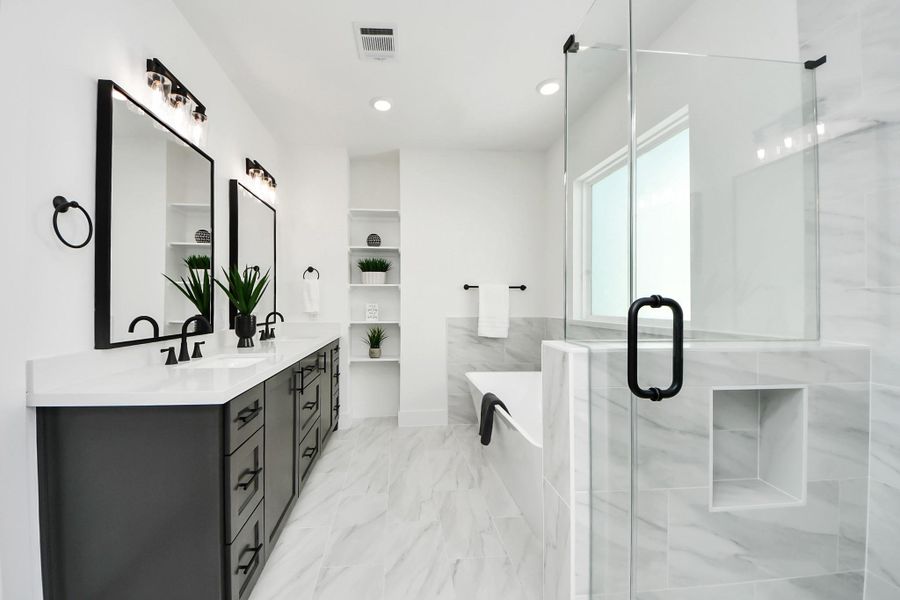 This bathroom features a sleek, modern design with a double vanity, large mirrors, and elegant black fixtures. It includes a spacious glass-enclosed shower and a freestanding bathtub. The room is bright with white and gray tones, creating a clean and sophisticated look. This bathroom features a sleek, modern design with a double vanity, large mirrors, and elegant black fixtures. It includes a spacious glass-enclosed shower and a freestanding bathtub. The room is bright with white and gray tones, creating a clean and sophisticated look.
