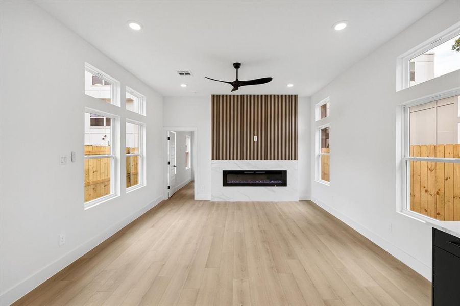 Unfurnished living room featuring a ceiling fan, light wood-style flooring, a premium fireplace, and recessed lighting