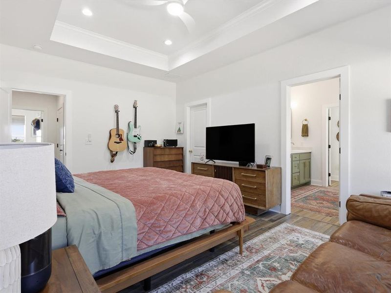 Bedroom with wood finished floors, ornamental molding, a tray ceiling, recessed lighting, and ceiling fan