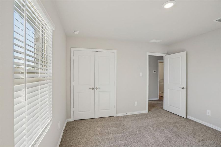 Unfurnished bedroom with light carpet, multiple windows, and a closet