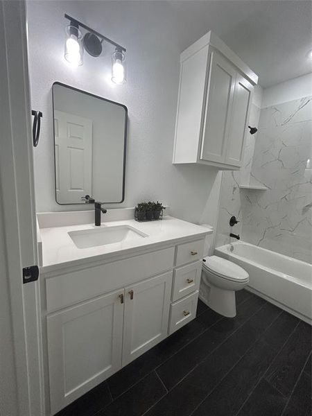 Full bathroom featuring vanity, tiled shower / bath combo, and toilet