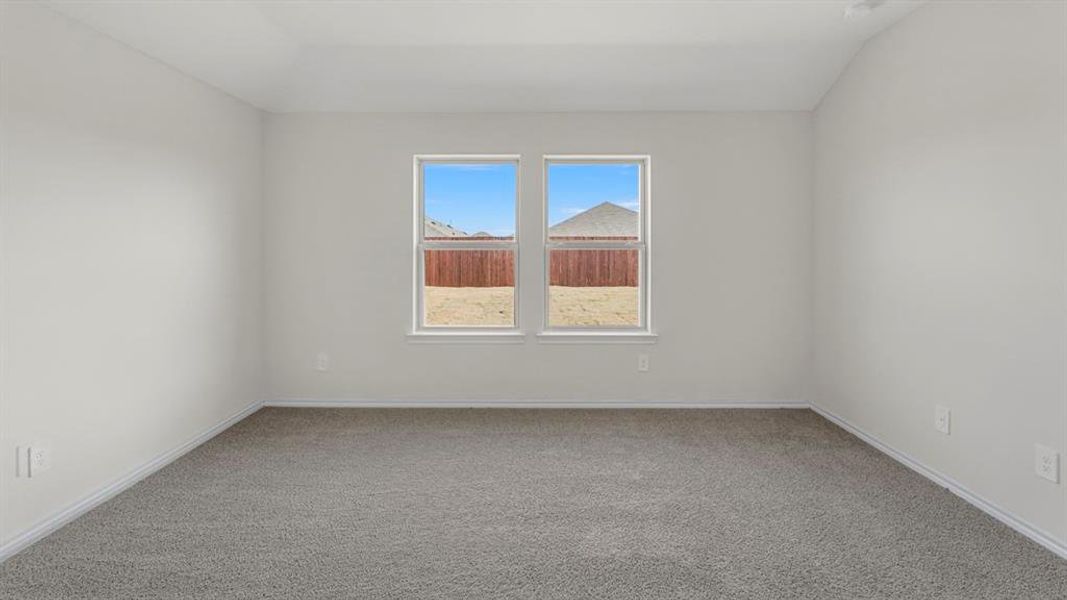 Bright interior room featuring neutral wall paint, gray carpet flooring, white baseboards, and two windows providing outdoor visibility