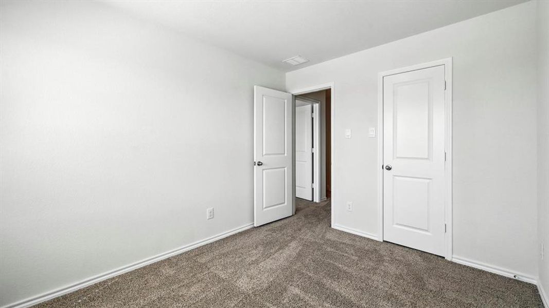 Neutral tone wall finish with a gray carpeted floor, white baseboards, and two paneled interior doors