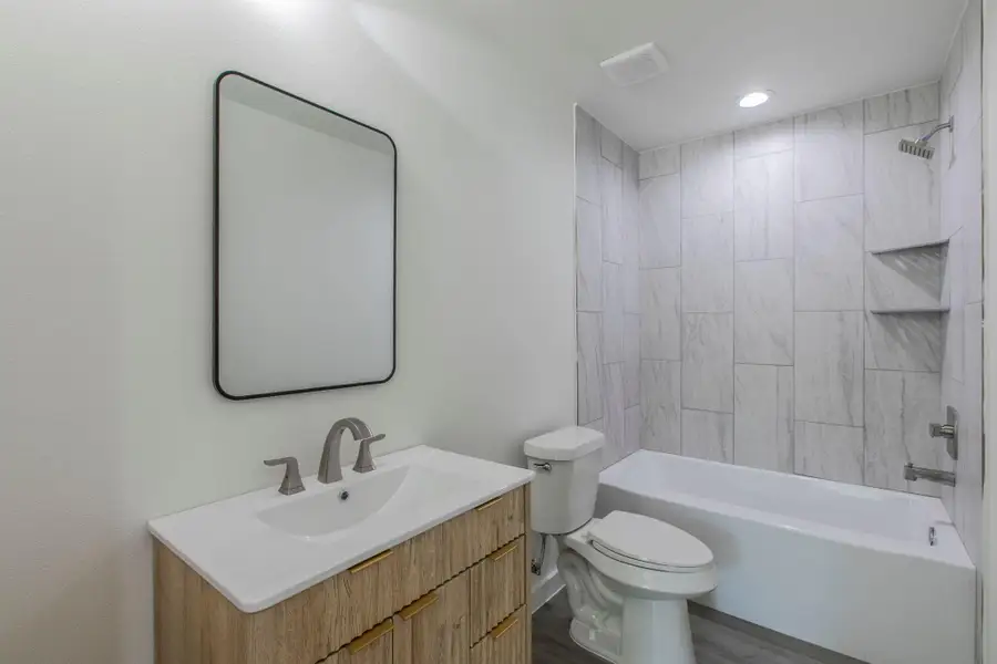 Bathroom with shower / bathtub combination, vanity, and dark wood-style flooring