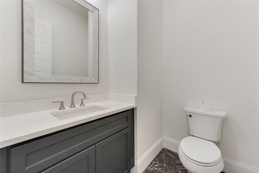 Vanity featuring a white countertop with an integrated rectangular sink, brushed nickel faucet, and dark gray cabinetry Vanity featuring a white countertop with an integrated rectangular sink, brushed nickel faucet, and dark gray cabinetry