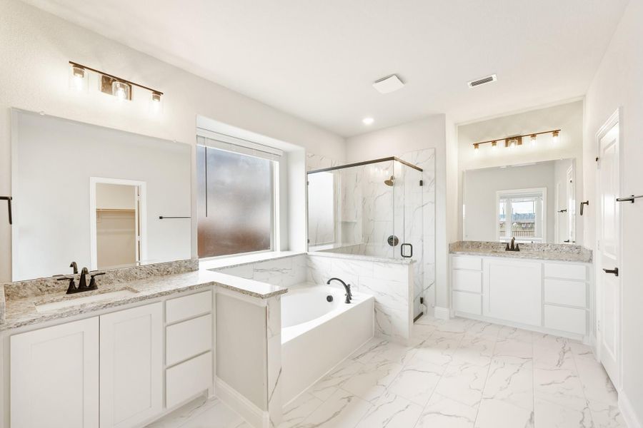 Master bathroom with dual vanities, soaking tub, glass shower, and white marble tile floors Master bathroom with dual vanities, soaking tub, glass shower, and white marble tile floors