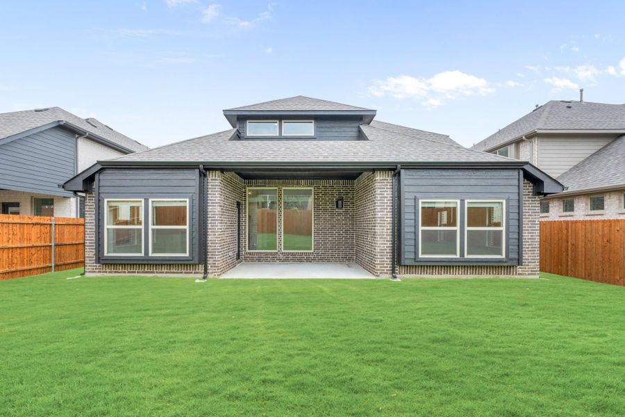 Rear exterior of single-story brick home with covered patio, large windows, and green lawn Rear exterior of single-story brick home with covered patio, large windows, and green lawn