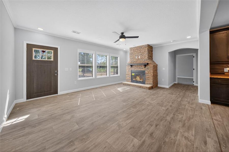 Unfurnished living room featuring crown molding, light wood-type flooring, ceiling fan, a fireplace, and recessed lighting Unfurnished living room featuring crown molding, light wood-type flooring, ceiling fan, a fireplace, and recessed lighting