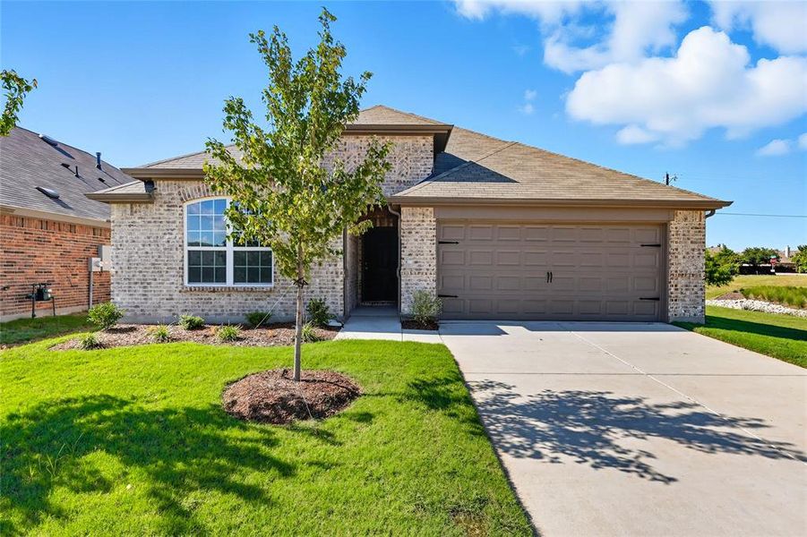 View of front of house with driveway, a front lawn, an attached garage, and brick siding