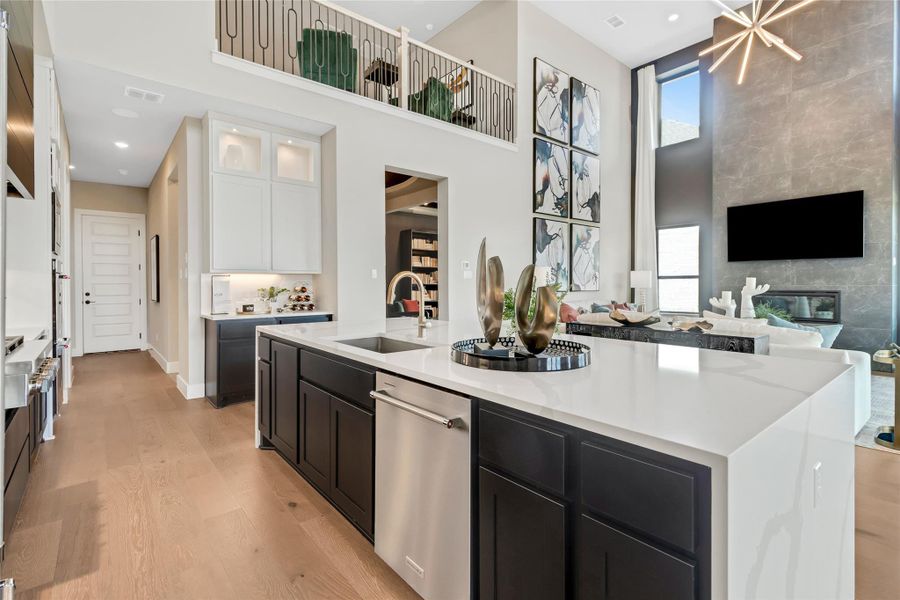 Kitchen featuring white cabinets, stainless steel dishwasher, light wood-style floors, healthy amount of natural light, and a high ceiling Kitchen featuring white cabinets, stainless steel dishwasher, light wood-style floors, healthy amount of natural light, and a high ceiling