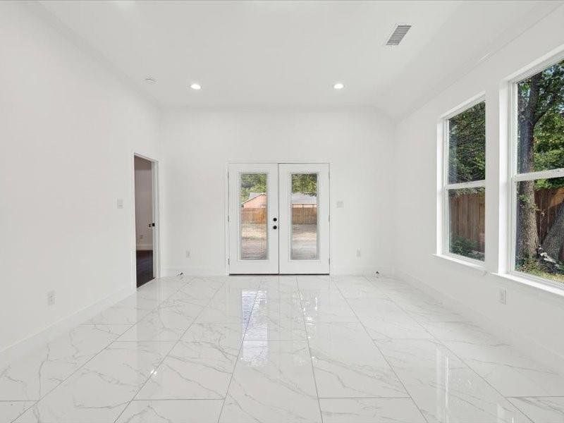 Tiled empty room with french doors and a healthy amount of sunlight