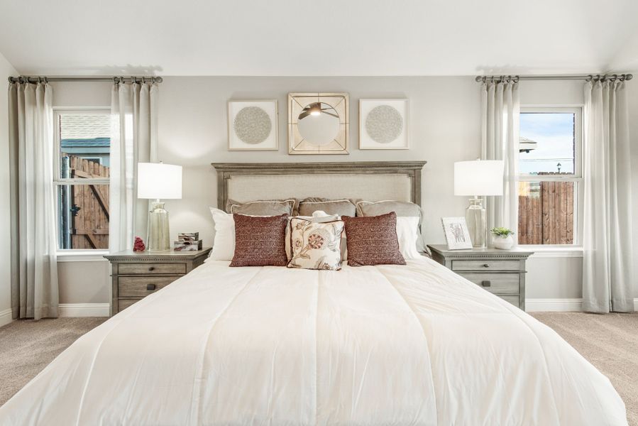 Bedroom with king bed, upholstered headboard, two nightstands, and windows with gray curtains on each side