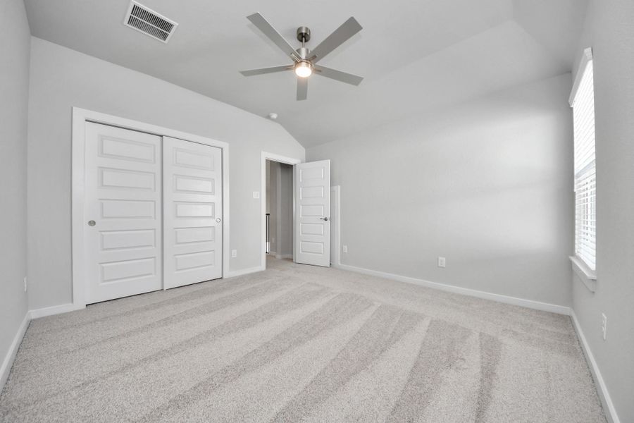 Secondary bedroom features plush carpeting, large windows that let in plenty of natural light, bright paint, and spacious closets.