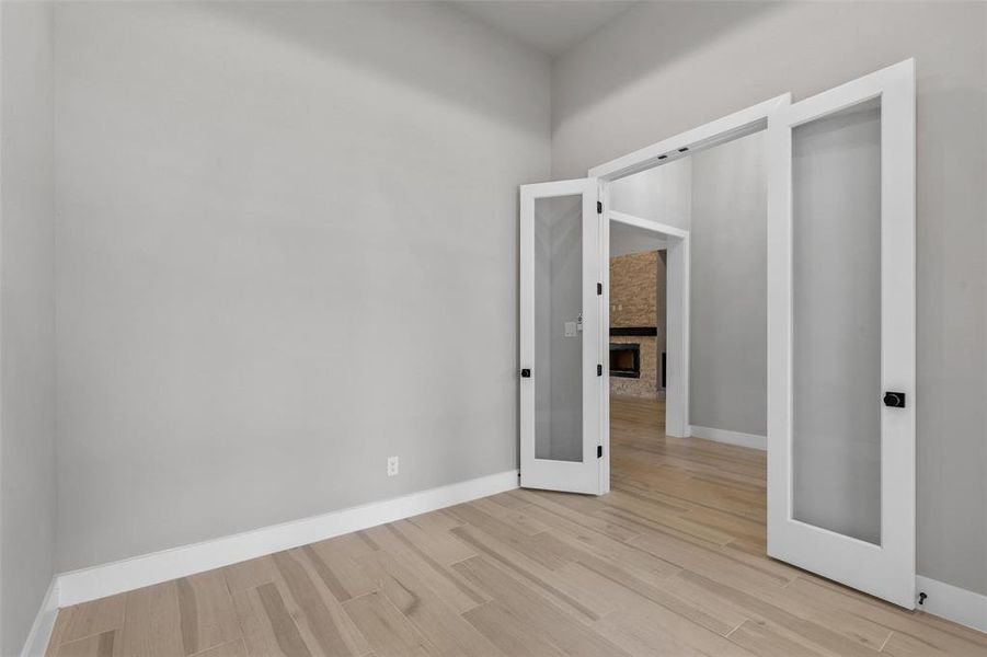 Unfurnished bedroom featuring a fireplace, light wood-type flooring, and a barn door