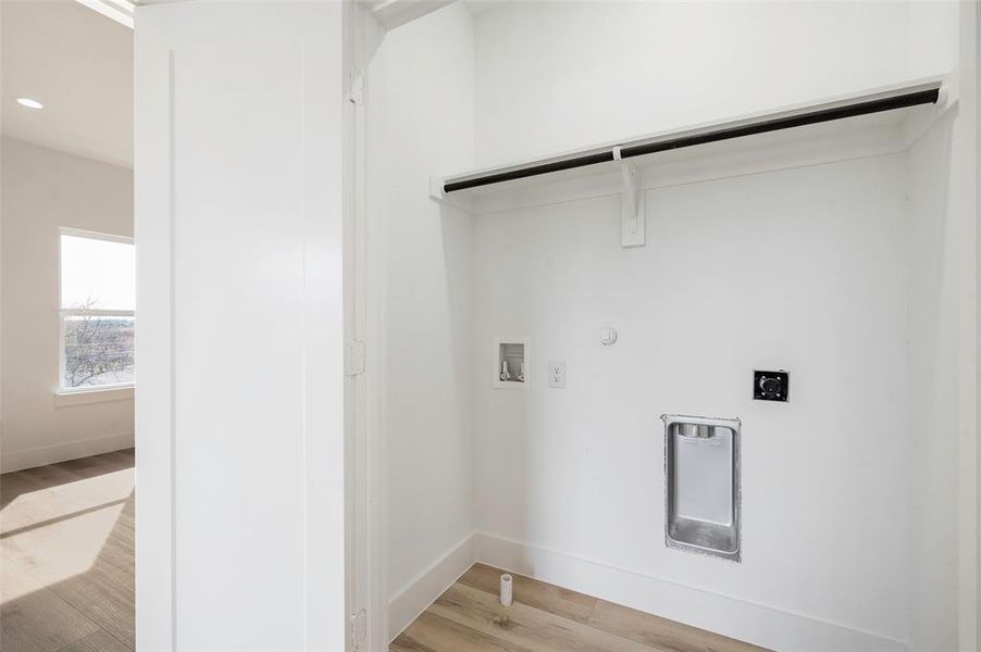 Washroom with electric dryer hookup, hookup for a gas dryer, light wood-type flooring, and washer hookup