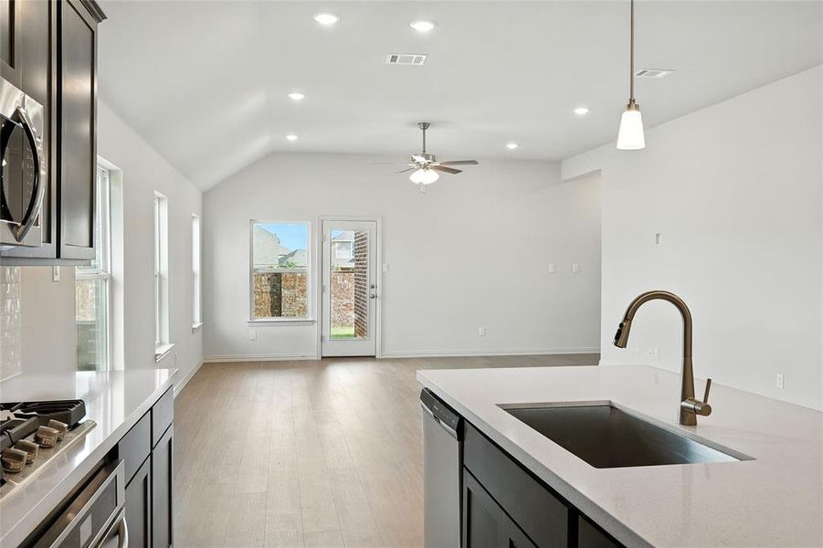 Kitchen featuring pendant lighting, light stone counters, light wood-style flooring, recessed lighting, and appliances with stainless steel finishes Kitchen featuring pendant lighting, light stone counters, light wood-style flooring, recessed lighting, and appliances with stainless steel finishes