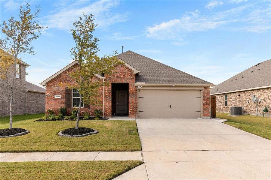 View of front of property with brick siding, a front yard, concrete driveway, and roof with shingles