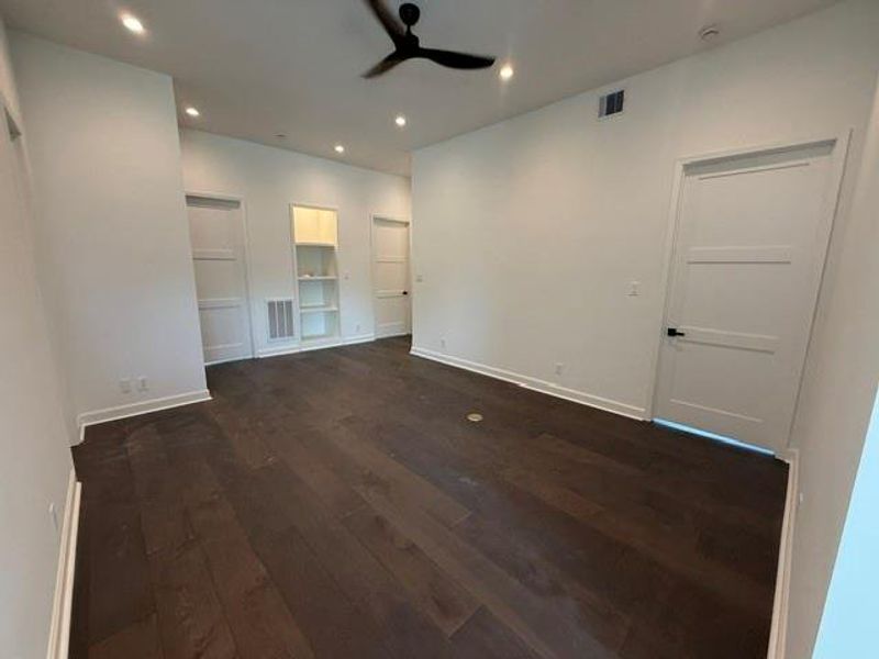 Another view of the spacious upstairs family room with sleek dark hardwood floors, recessed lighting, and modern ceiling fan, offering a contemporary and airy feel.