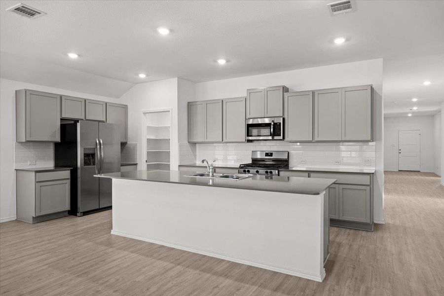 A pristine modern kitchen features sleek gray cabinetry and stainless steel appliances, anchored by a central island with an integrated sink. A pristine modern kitchen features sleek gray cabinetry and stainless steel appliances, anchored by a central island with an integrated sink.